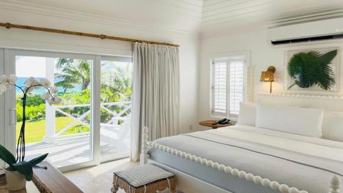 a bedroom with a bed and a large window at The Potlatch Club Boutique Hotel in Governorʼs Harbour