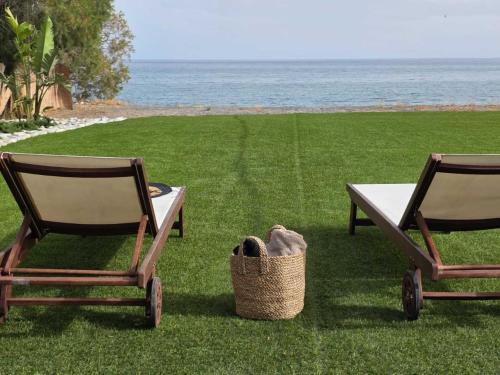 two chairs and a table and a basket on the grass at JM Dēos Suites in Keratokampos