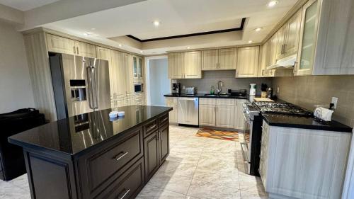 a large kitchen with wooden cabinets and black counter tops at Massive Luxury Retreat with Gym, Sauna, Games and More in Mississauga