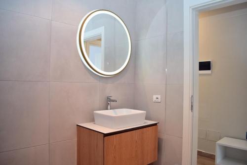 une salle de bain avec un lavabo et un miroir au mur dans l'établissement San Pietro Happy Stay 300, à Lalzit Bay