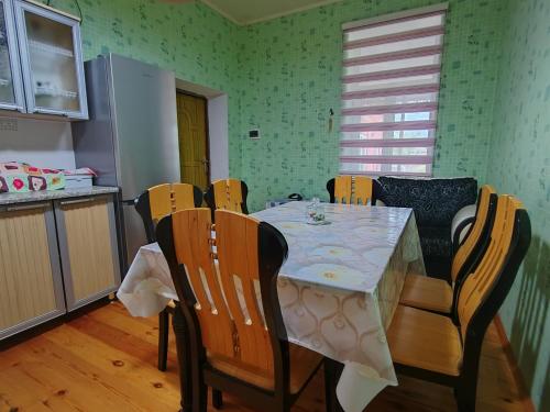 a dining room table with chairs and a table and a kitchen at Sahil Evi in Lankaran