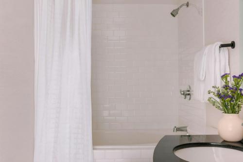 a white bathroom with a sink and a bath tub at The Sunset Hotel West End, Sonder by Marriott Bonvoy in Vancouver