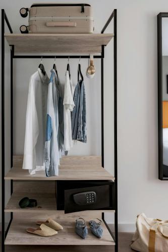 a walk in wardrobe with clothes and shoes at The Henry Hotel Bayswater, Sonder by Marriott Bonvoy in London