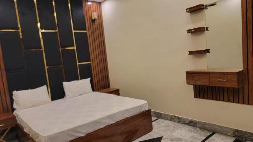 a small bedroom with a bed and a wooden headboard at Elegant Guest House Karachi in Karachi