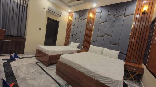 a bedroom with two beds and a wall at Elegant Guest House Karachi in Karachi