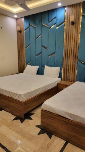 two beds in a room with blue walls at Elegant Guest House Karachi in Karachi