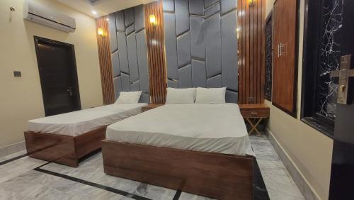 a room with two beds and a desk and a window at Elegant Guest House Karachi in Karachi