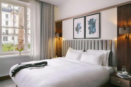 a bedroom with a large white bed and a window at The Voyage Hotel Paddington in London