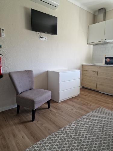 a living room with a chair and a tv on the wall at Casa das Portas in Azinhaga