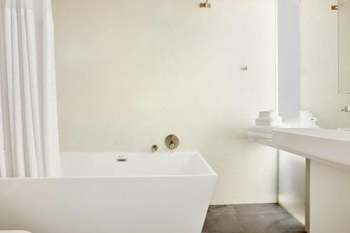 a white bathroom with a tub and a sink at The Slate Hotel Downtown, Sonder by Marriott Bonvoy in Toronto