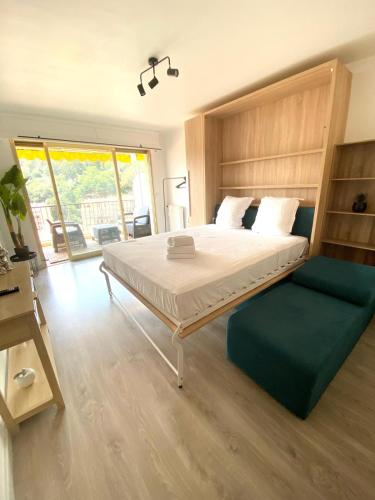 - une chambre avec un grand lit et un canapé vert dans l'établissement Le Patricia studio balcon calme vue clim, à Menton