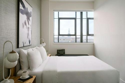a white bedroom with a large bed and a window at Sonder by Marriott Bonvoy Le Guerin Apartments Le Plateau-Mont-Royal in Montréal