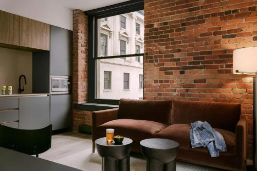 a living room with a brown couch and a brick wall at Sonder by Marriott Bonvoy Apollon Apartments Old Montreal in Montréal