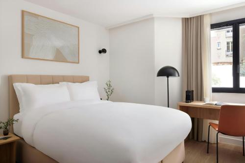 a bedroom with a large white bed and a desk at Yvette Hotel Porte de Versailles, Sonder by Marriott Bonvoy in Vanves