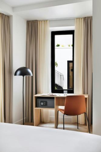 a room with a desk with a chair and a mirror at Yvette Hotel Porte de Versailles, Sonder by Marriott Bonvoy in Vanves