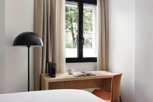 a bedroom with a desk with a lamp and a window at Yvette Hotel Porte de Versailles, Sonder by Marriott Bonvoy in Vanves