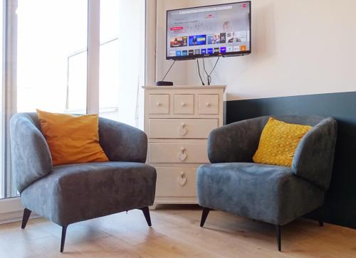 - deux chaises et une télévision dans le salon dans l'établissement La brise, belle terrasse hyper-centre by Primo, à Le Touquet-Paris-Plage