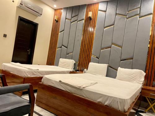 a room with two beds and a chair at Elegant Guest House Karachi in Karachi