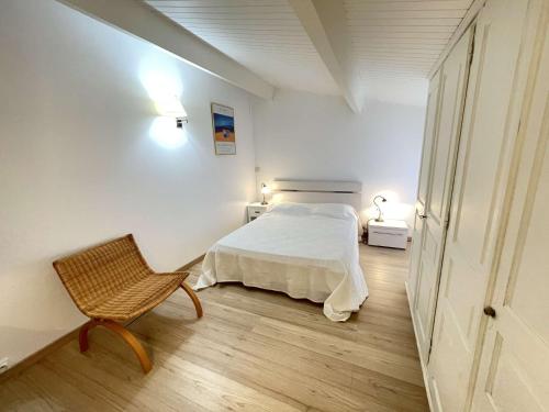 une chambre blanche avec un lit et une chaise dans l'établissement Appartement F3 Sampiero 2 Pietrosella, à Porticcio