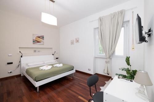 a white bedroom with a bed and a desk at Ostia Bella Apartment in Lido di Ostia