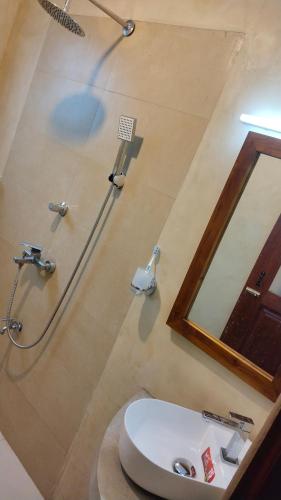 a bathroom with a shower and a sink and a mirror at Holiday Home Ragama in Ragama