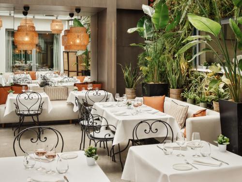 a restaurant with white tables and chairs and plants at Hôtel De Sers Champs Elysées Paris in Paris