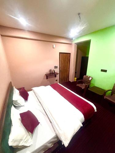 a bedroom with a large white bed and a green wall at J C Legacy in Chitkul