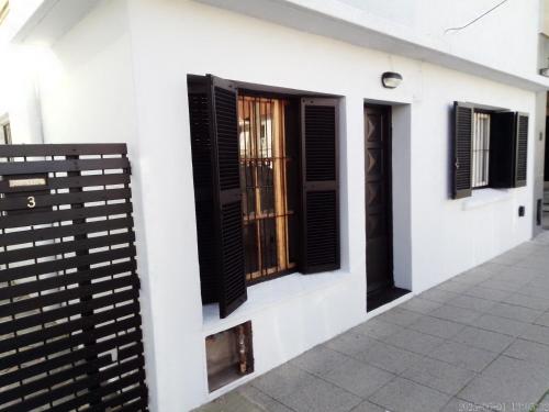 a white building with black windows and a fence at house city in Mar del Plata