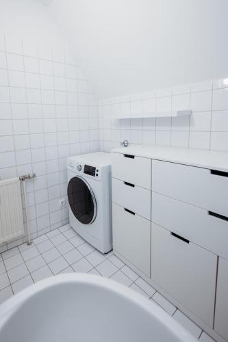 a washing machine in a white tiled bathroom at FREE Parking, Nespresso, Netflix in Wels