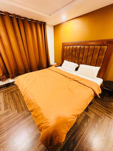 a bedroom with a large bed with yellow walls at Hotel Luxy Skardu in Rondu