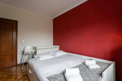 a bedroom with a white bed with a red wall at GuestReady - Restful stay in Vila Nova de Gaia in Vila Nova de Gaia