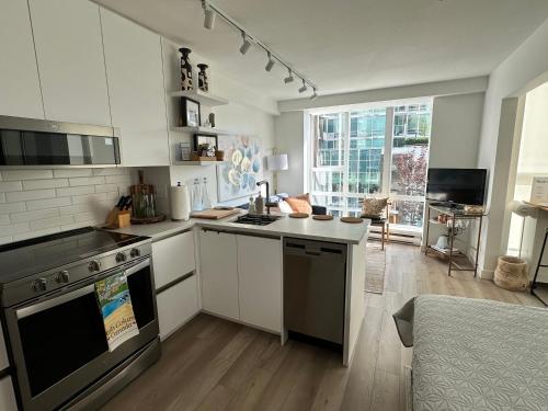a kitchen with white cabinets and a stove top oven at Executive Studio in Vancouver