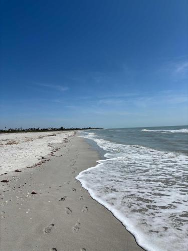 a beach with footprints in the sand and the ocean at Blind Pass C106 - Upgraded Ground Floor Residence at Blind Pass in Sanibel