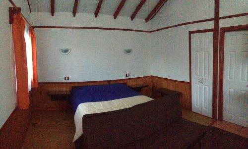 een kleine slaapkamer met een bed en een raam bij Cabañas El Mirador in Hornopiren