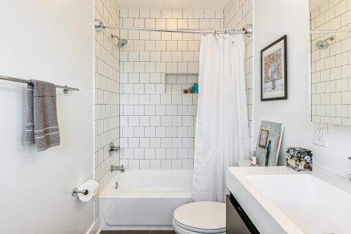 ワシントンにあるWalkable Columbia Heights Condo with Rooftop Deck!のバスルーム(白いバスタブ、トイレ、シンク付)