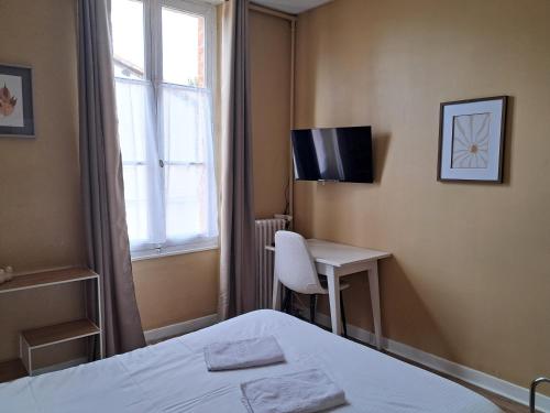 a bedroom with a bed and a desk and a window at Hotel Le Normandy in Beaumont-de-Lomagne