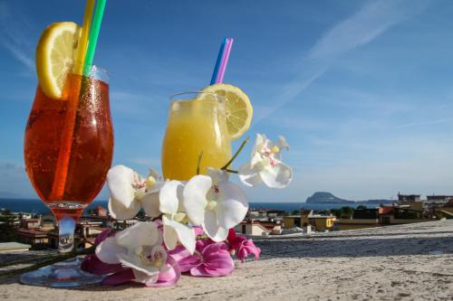 two cocktails sitting on a table with flowers on the beach at Hotel Santa Marta in Pozzuoli