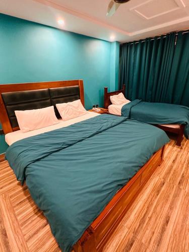 two beds in a room with blue walls at Hotel Luxy Skardu in Rondu