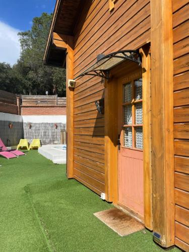 a wooden building with a red door on a lawn at Les Suites in Santa María de Palautordera