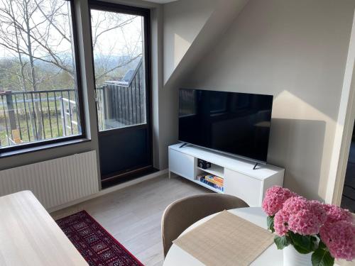 a living room with a television and a table with flowers at PALEO House in Kristianstad