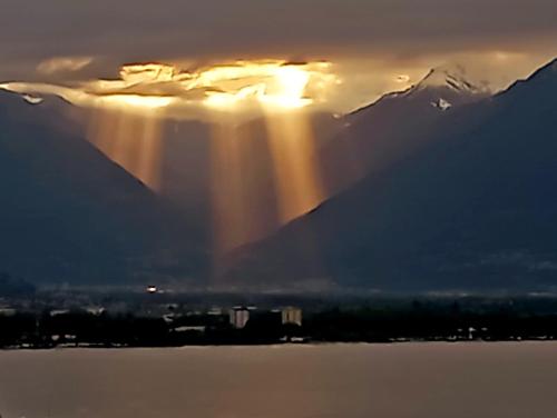 a rainbow in the sky over the water with mountains at Bell orizzonte in Locarno
