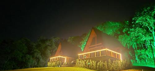 a building lit up at night with green lights at Pousada Lua chalé in Blumenau