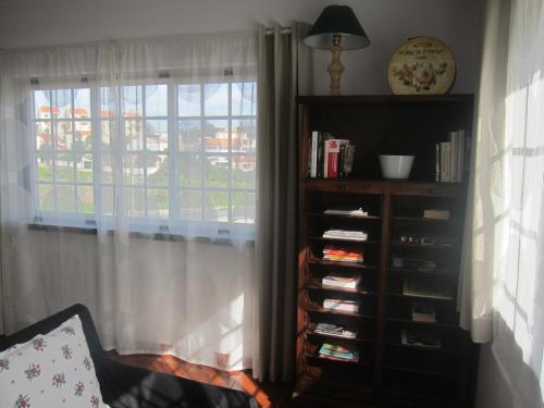a book shelf in a living room with a window at Casa das Hortênsias - Charming Guest House in Sintra