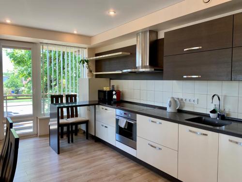 a kitchen with white cabinets and black counter tops at Sunny Lotus Apartamentai in Druskininkai