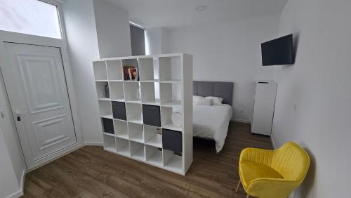 a bedroom with a white book shelf and a yellow chair at Casa da Praça in Condeixa a Nova