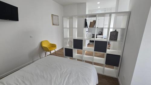 a bedroom with a bed and a yellow chair at Casa da Praça in Condeixa a Nova