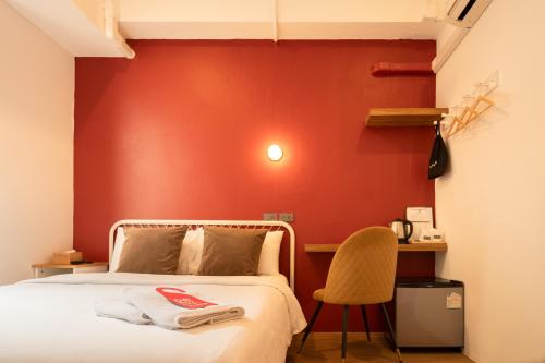 a bedroom with a red wall with a bed and a chair at House Of Papa Bangkok Siam in Bangkok