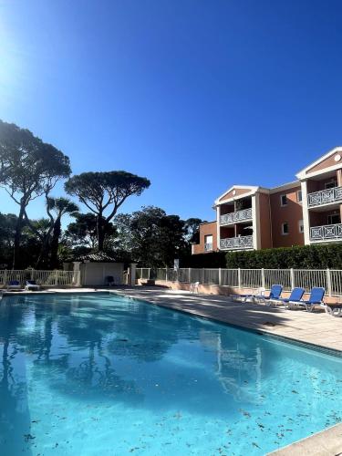 une piscine avec des chaises et un bâtiment en arrière-plan dans l'établissement appartement cosy avec piscine, à Saint-Raphaël