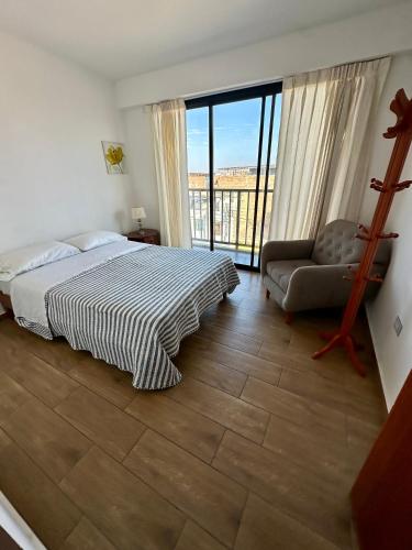 a bedroom with a bed and a chair and a window at DPTO de 2 Dorm y Terraza Vista al Mar in Pimentel