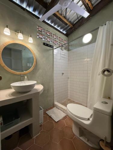 a bathroom with a sink and a toilet and a mirror at Hostal Tia Reyna in El Zonte
